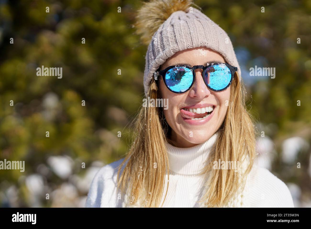 Donna sorridente con la lingua fuori in inverno Foto Stock