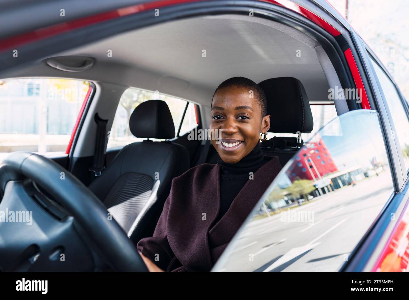 Felice giovane donna seduta in auto Foto Stock
