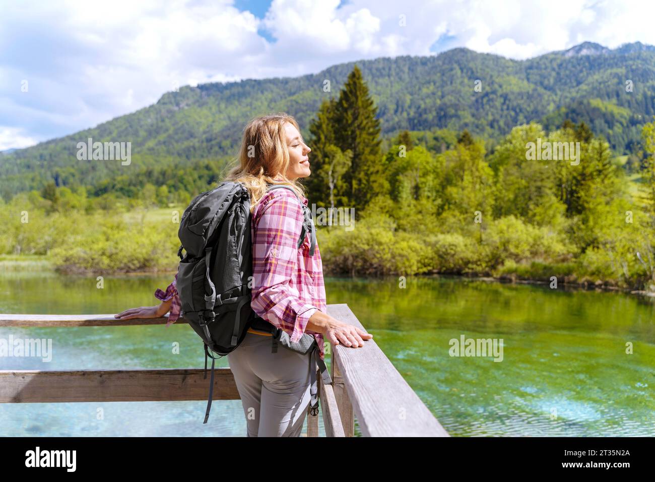 Backpacker con gli occhi chiusi godendosi di fronte al fiume e alle montagne Foto Stock