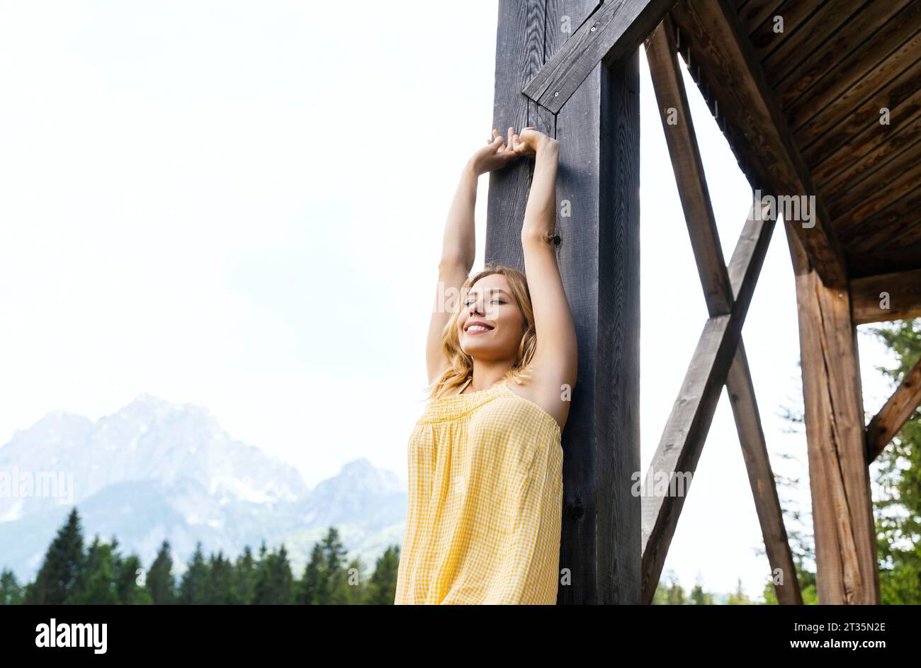 Donna con le braccia alzate appoggiata su una struttura in legno nella riserva naturale di Zelenci Foto Stock