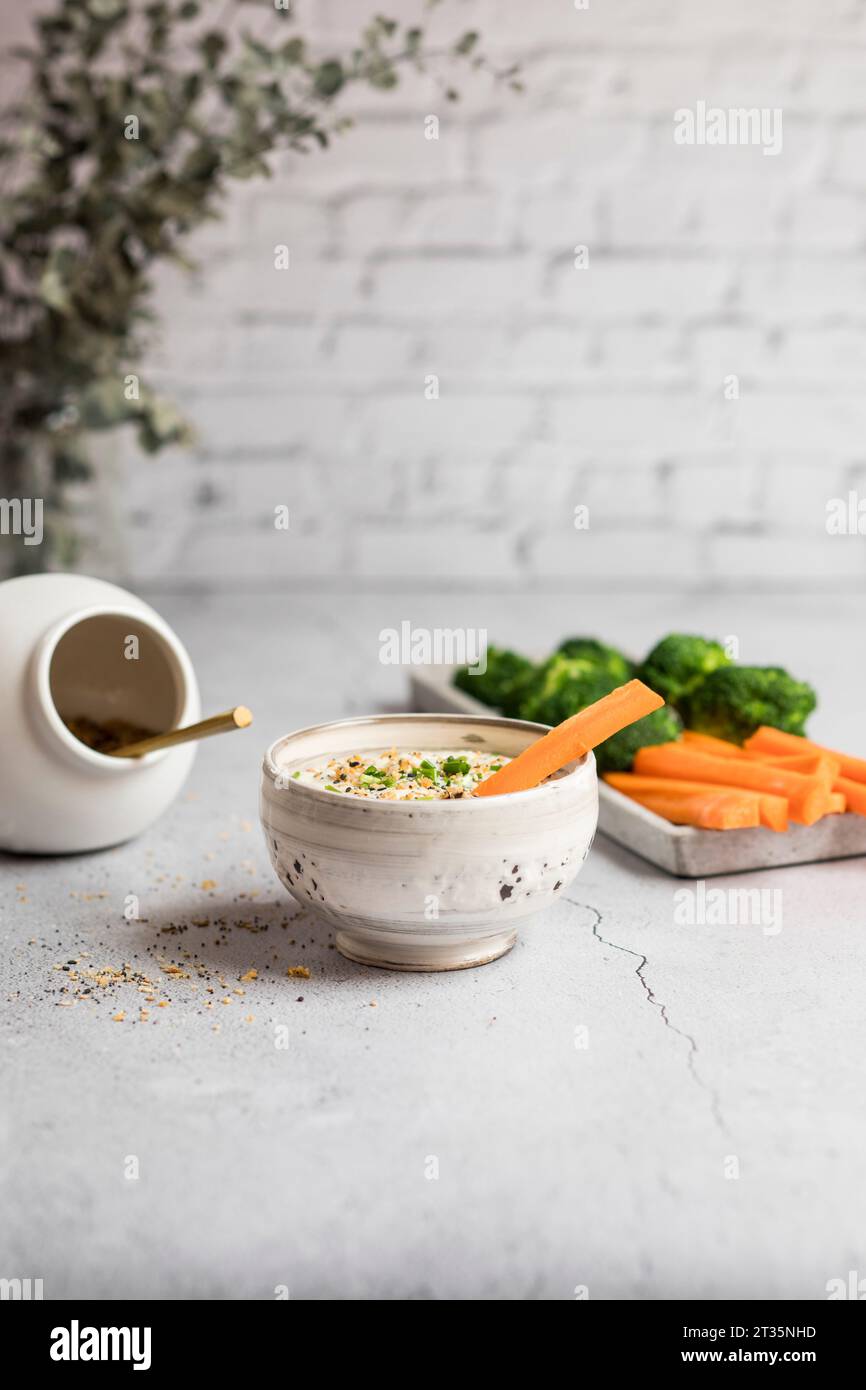 Ciotola di salsa al miele di feta, carote crude e broccoli Foto Stock