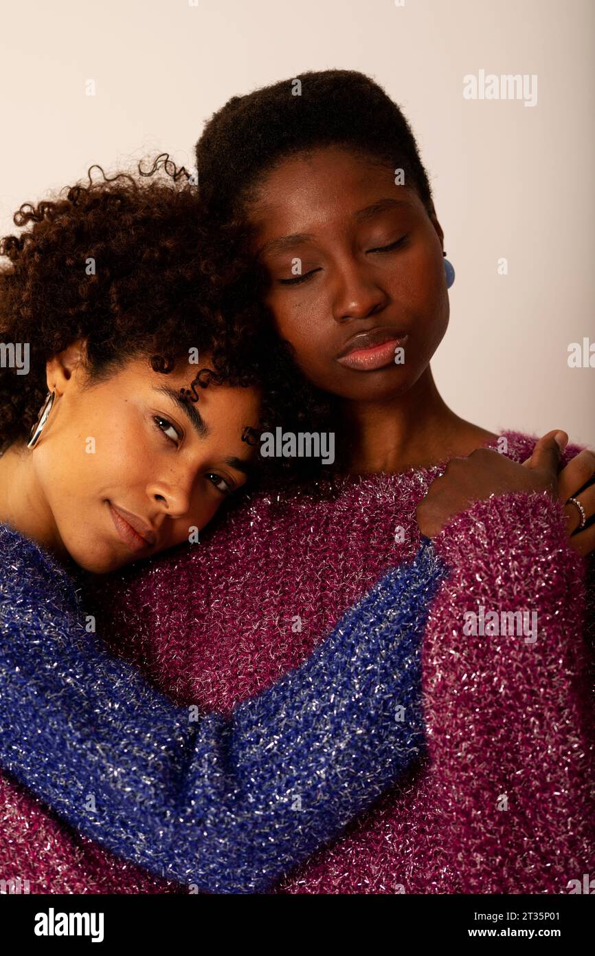 Giovani donne che si abbracciano su sfondo beige Foto Stock