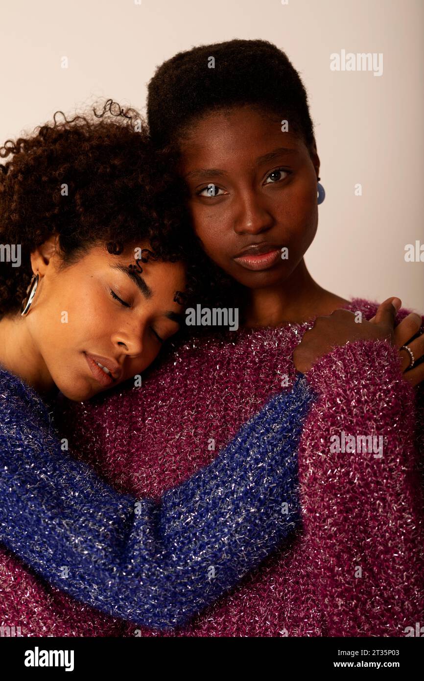 Donne che abbracciano su sfondo beige Foto Stock