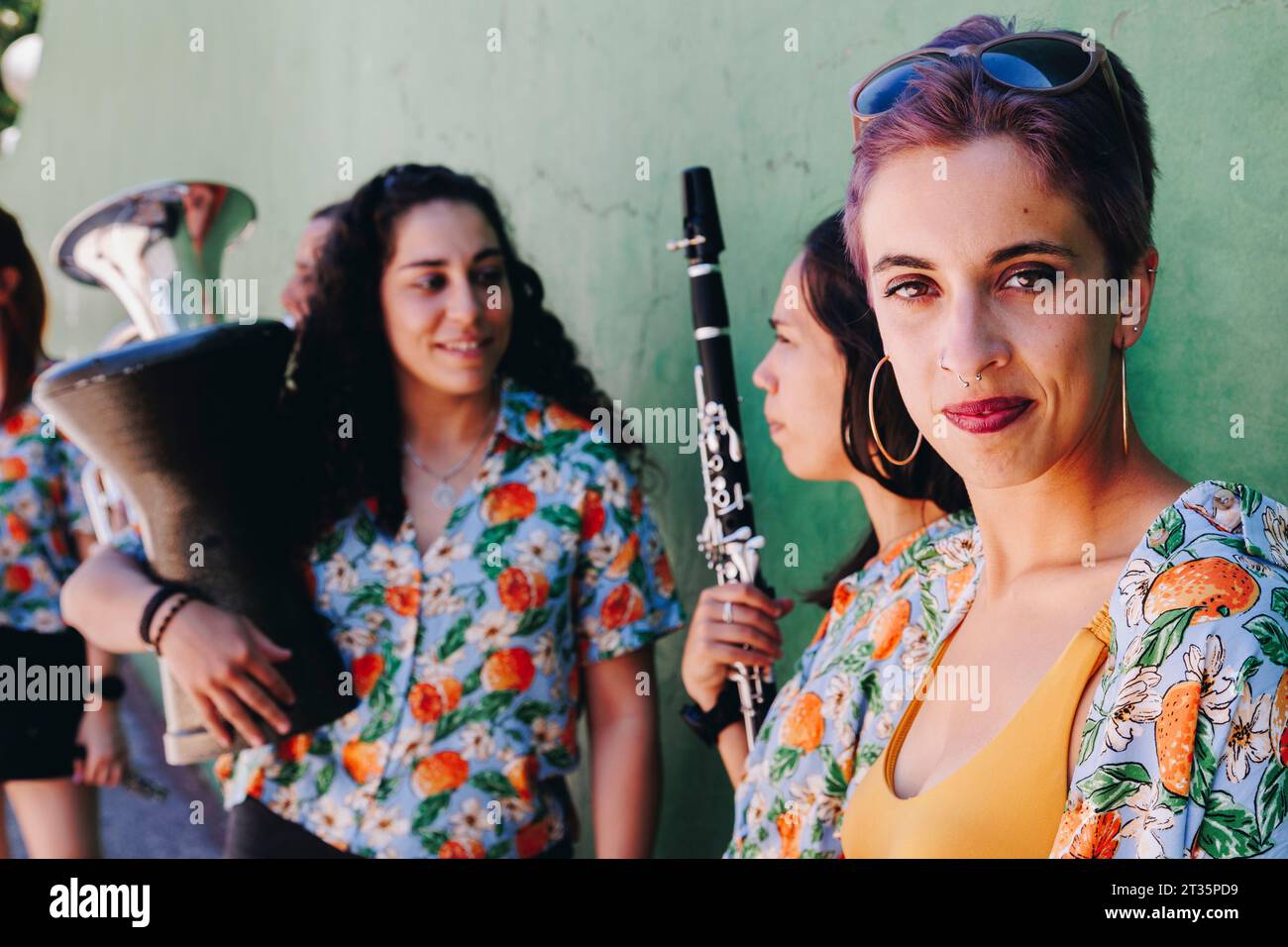 Donna hipster con gruppo folk che tiene in mano strumenti musicali Foto Stock
