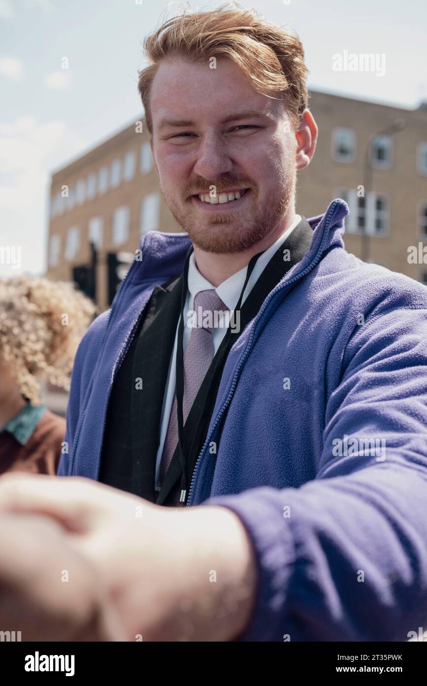 Un uomo d'affari sorridente che fa stretta di mano in strada Foto Stock