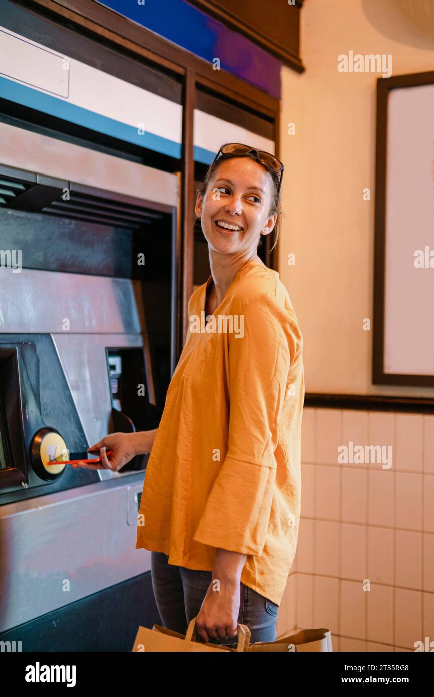 Donna sorridente che preleva denaro dal bancomat Foto Stock