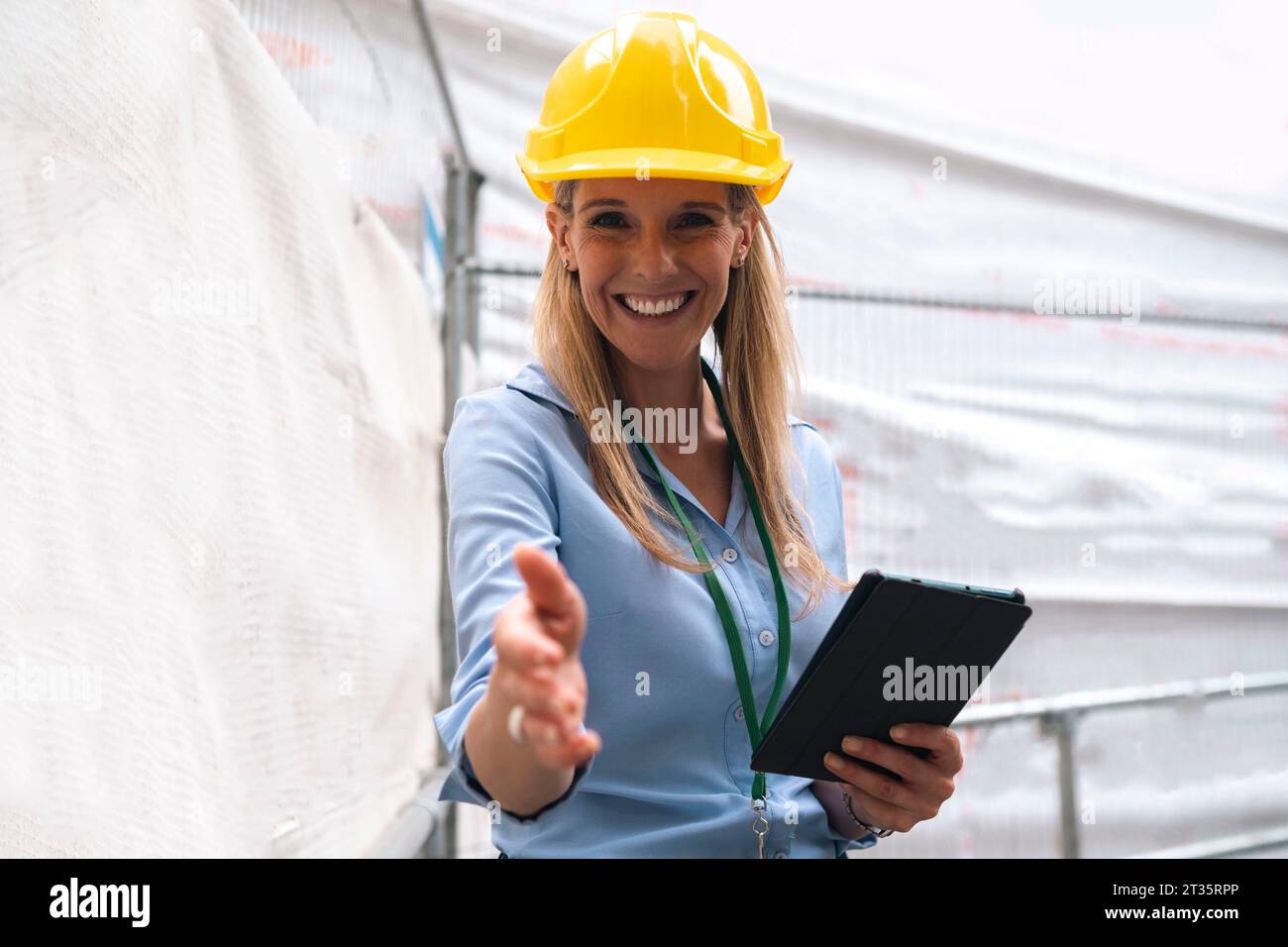 Ingegnere sorridente che fa una stretta di mano tenendo in mano un tablet PC Foto Stock