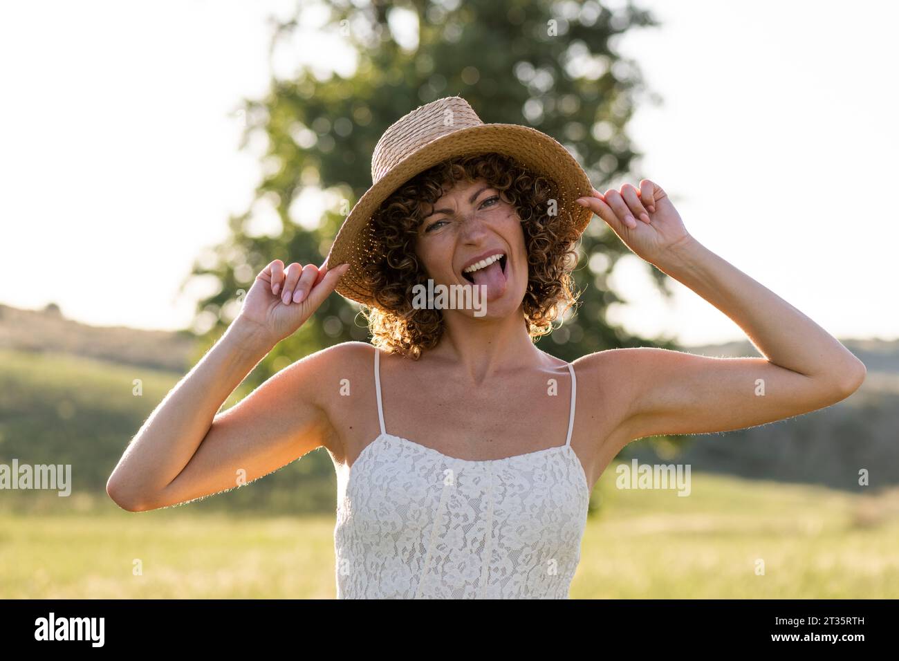 Donna che indossa un cappello che sporge la lingua nelle giornate di sole Foto Stock