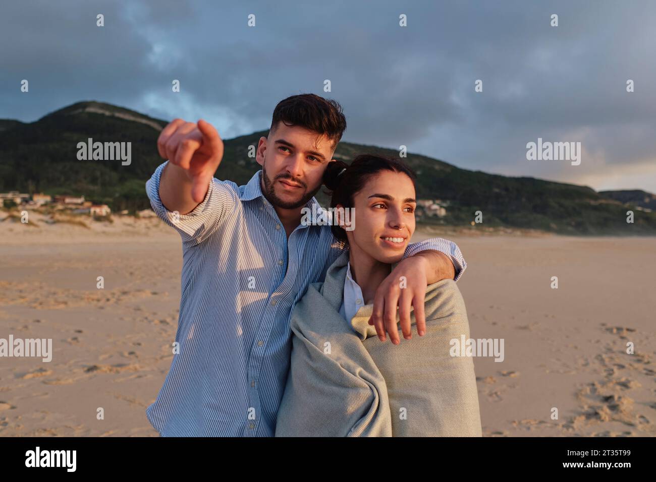 Uomo che punta con il braccio intorno alla ragazza in spiaggia Foto Stock