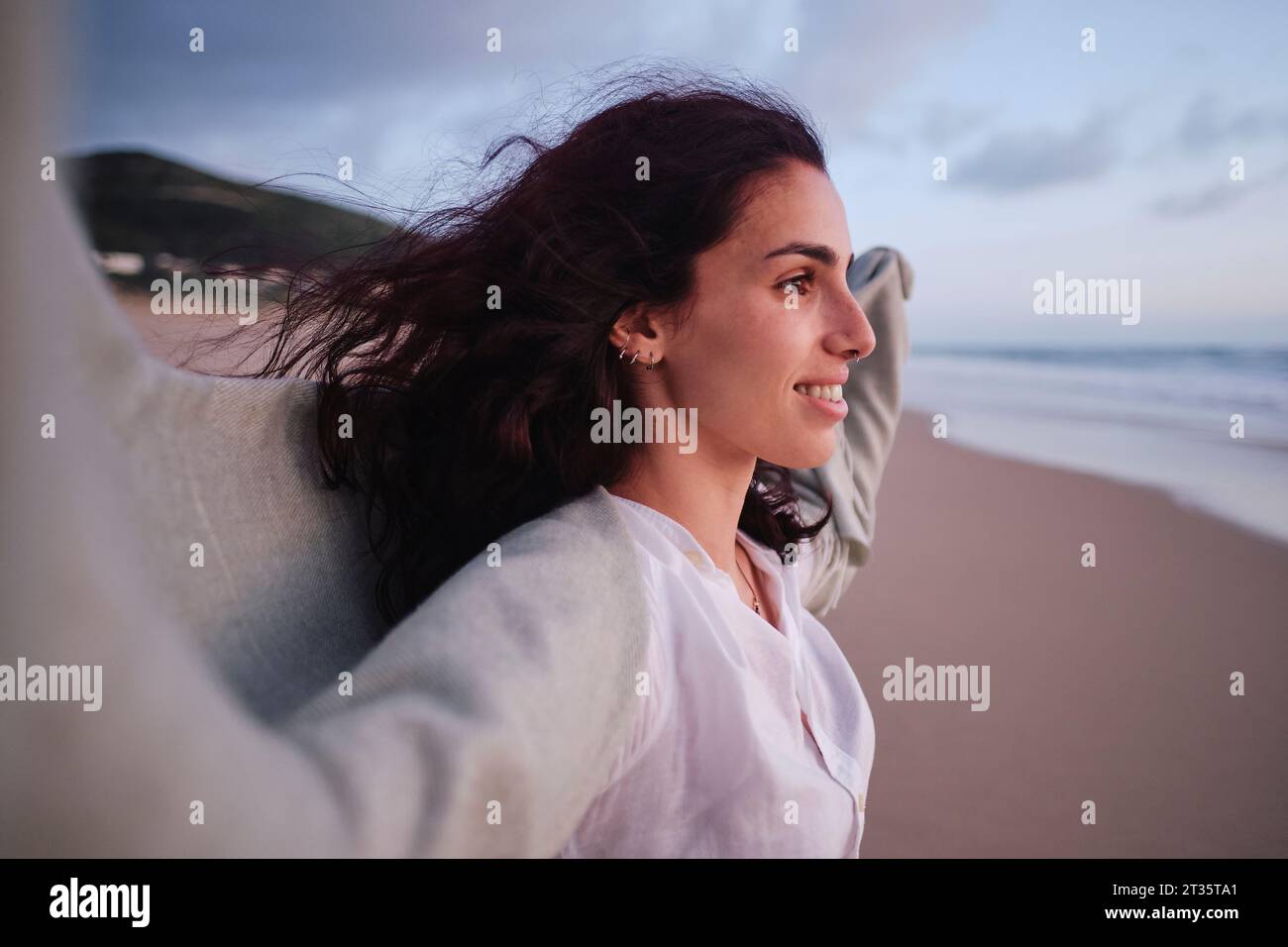 Donna sorridente che trascorre il tempo libero in spiaggia Foto Stock