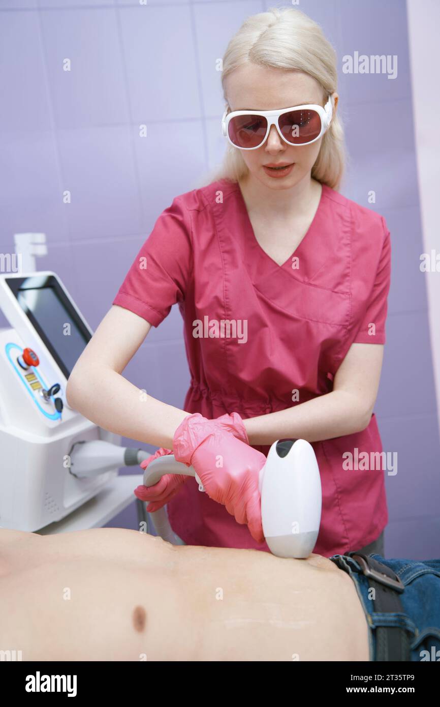 Dermatologo che effettua il trattamento di depilazione del paziente in clinica Foto Stock