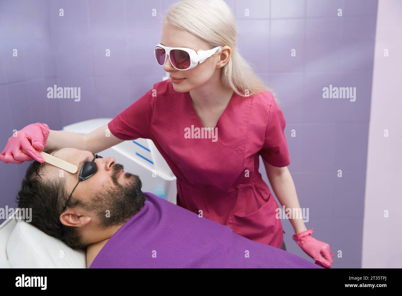 Dermatologo che fa il trattamento di depilazione del cliente in clinica Foto Stock