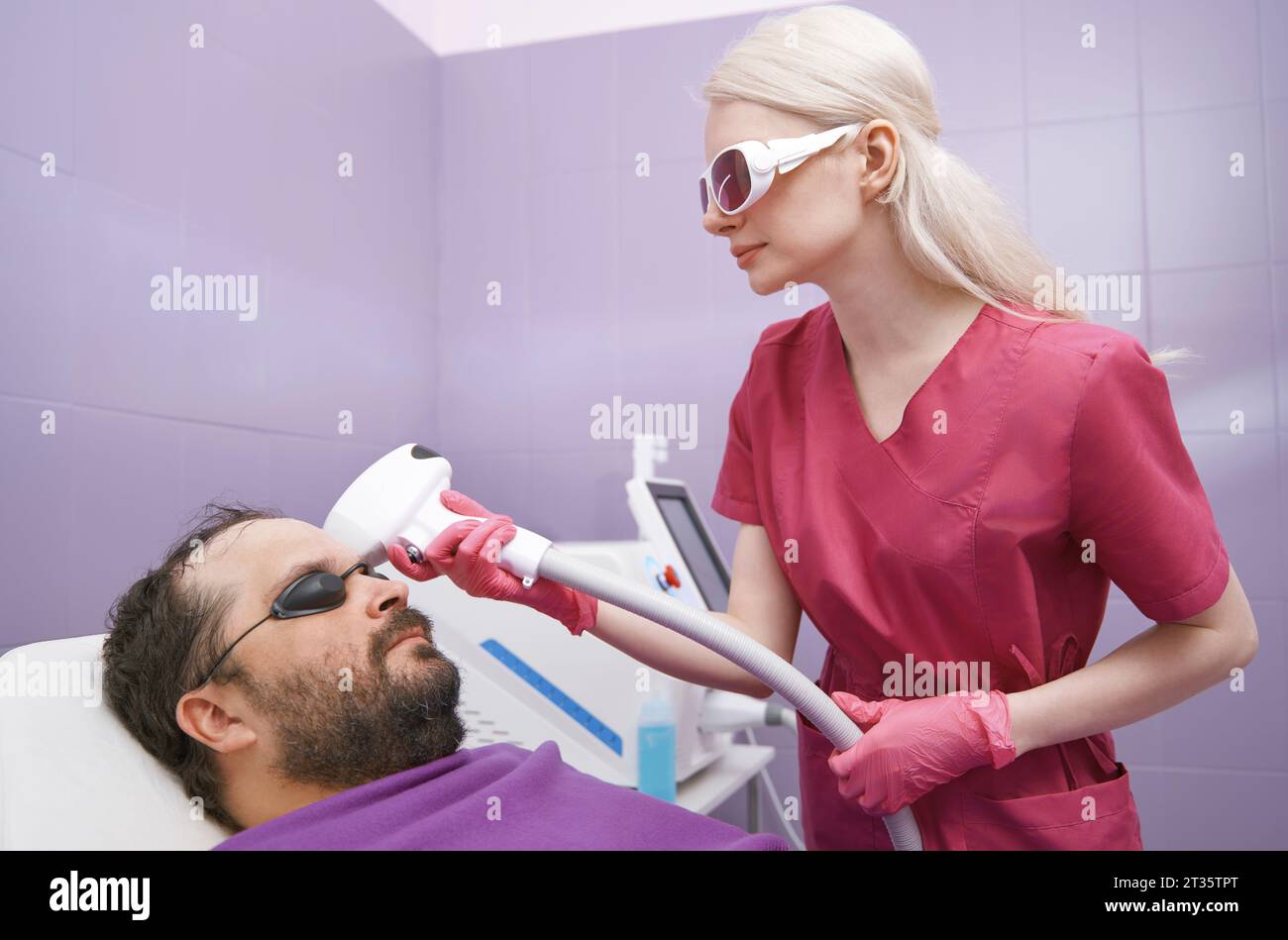 Medico che fa il trattamento di depilazione laser del cliente in clinica Foto Stock
