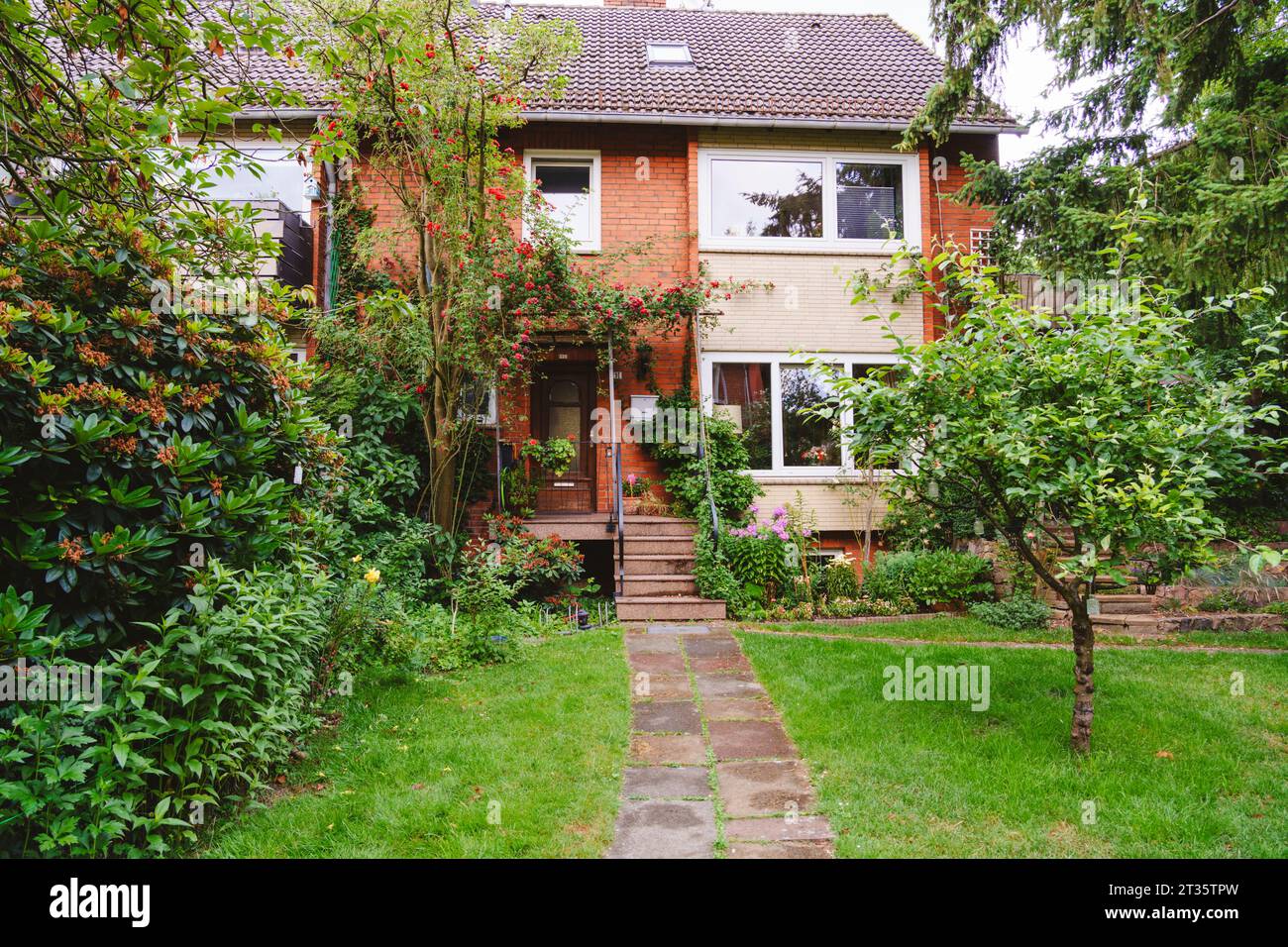 Casa in mattoni con piante e alberi Foto Stock