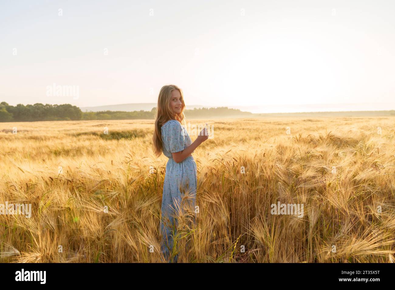 Ragazza sorridente con capelli lunghi in mezzo al grano in campo Foto Stock