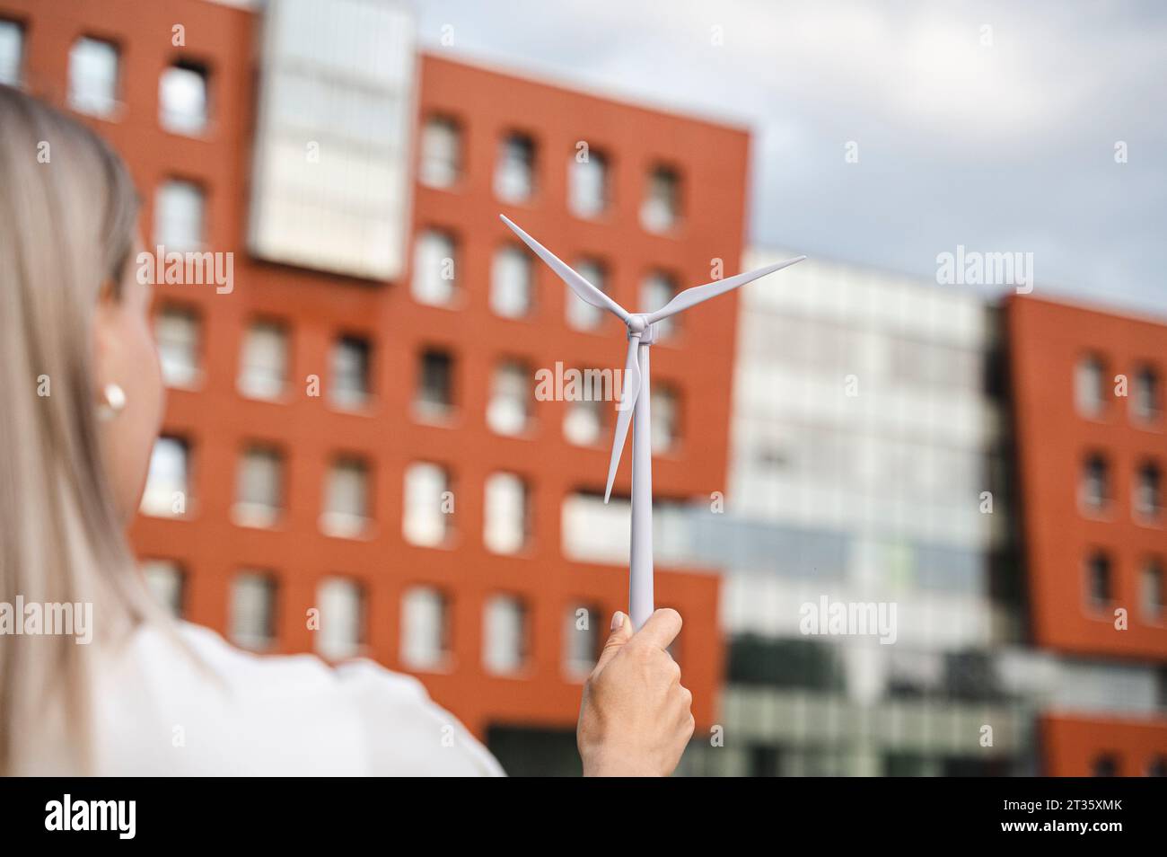 Donna d'affari con un modello di turbina eolica di fronte all'edificio Foto Stock