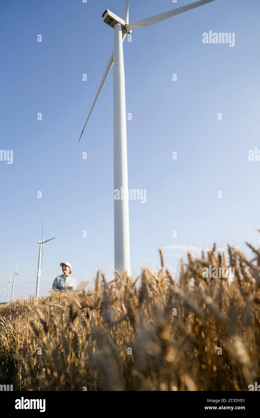 Agronomo in piedi di fronte alle turbine eoliche Foto Stock Agronomo in piedi di fronte alle turbine eoliche Foto Stock