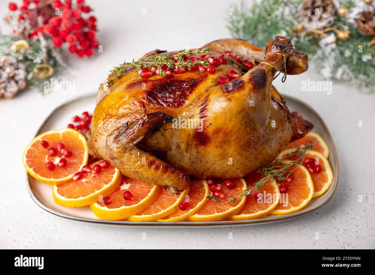 Pollo intero cotto al forno con crosta croccante e appetitosa con melograno e arancia rossa. Piatto tradizionale di Capodanno e Natale. Foto Stock