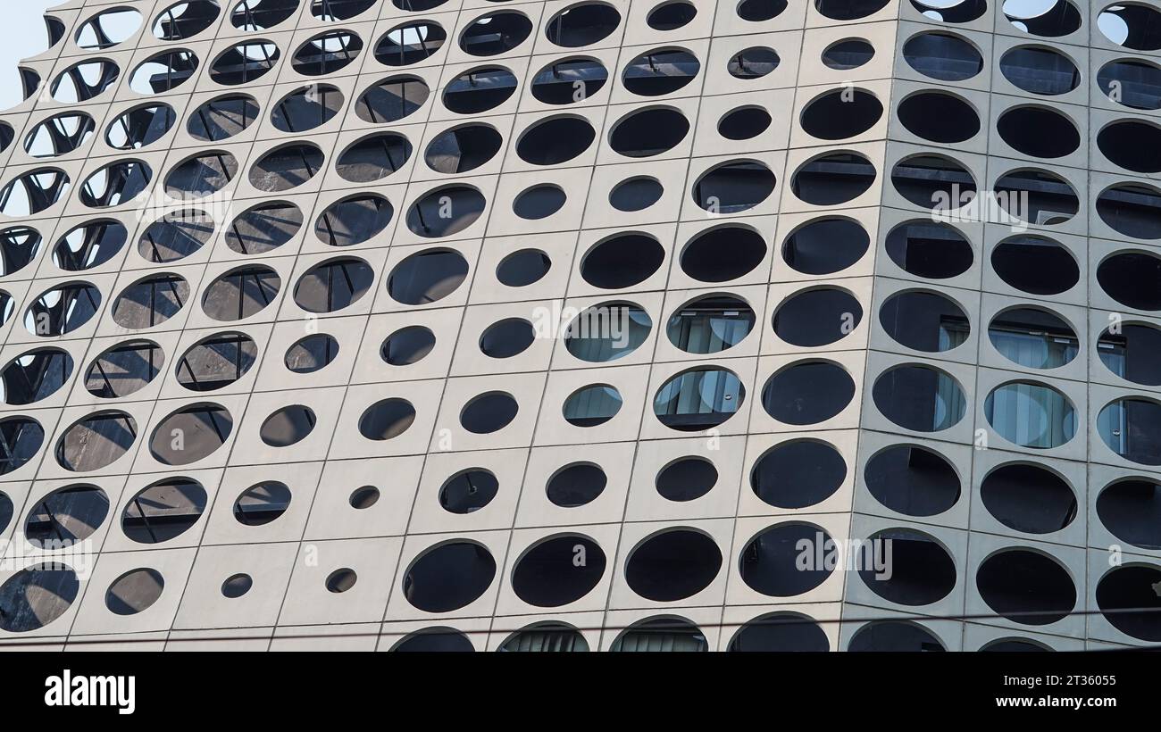 Un torreggiante edificio grigio con ornamenti che formano un cerchio lungo le sue pareti Foto Stock