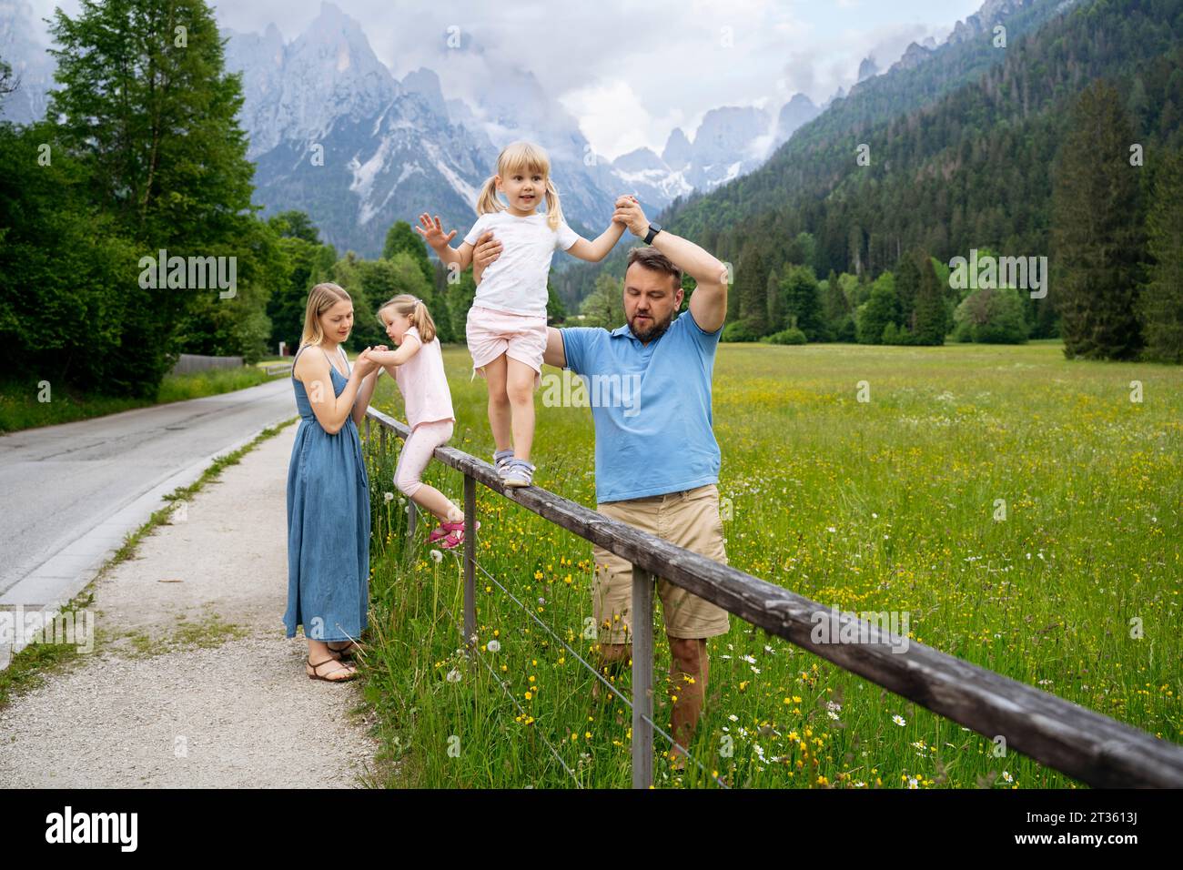 Genitori che sostengono le figlie che giocano sulle ringhiere Foto Stock