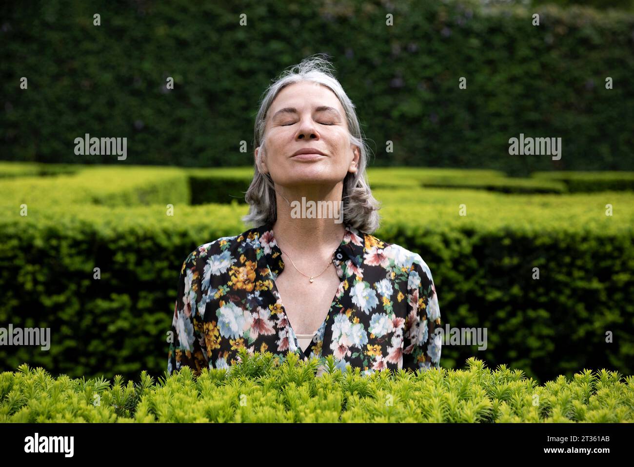 Donna anziana che immagina con gli occhi chiusi nel parco Foto Stock