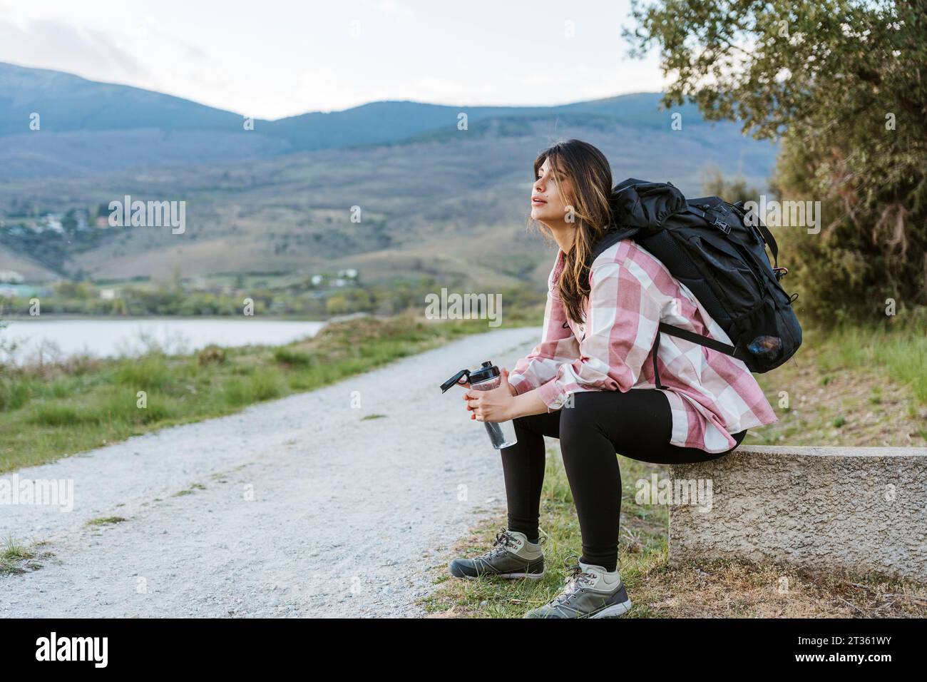 Un turista stanco che si prende una pausa seduto al bordo della strada Foto Stock