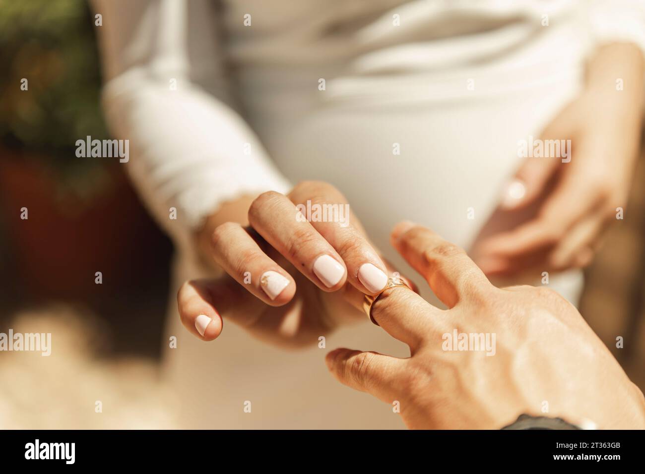 Mano della sposa che mette l'anello di nozze al dito dello sposo Foto Stock