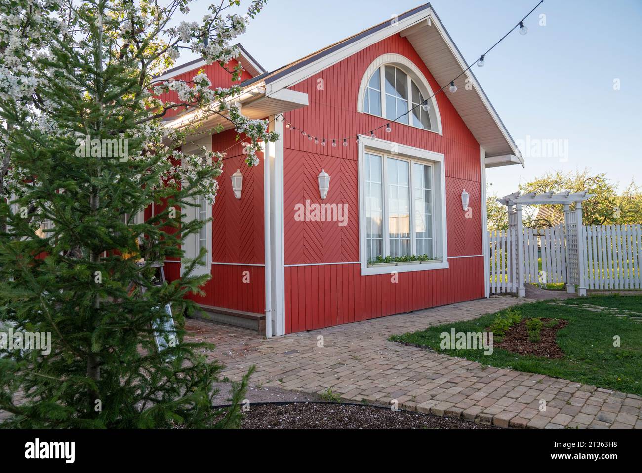 Casa rossa con luci a corda vicino agli alberi nel cortile posteriore Foto Stock