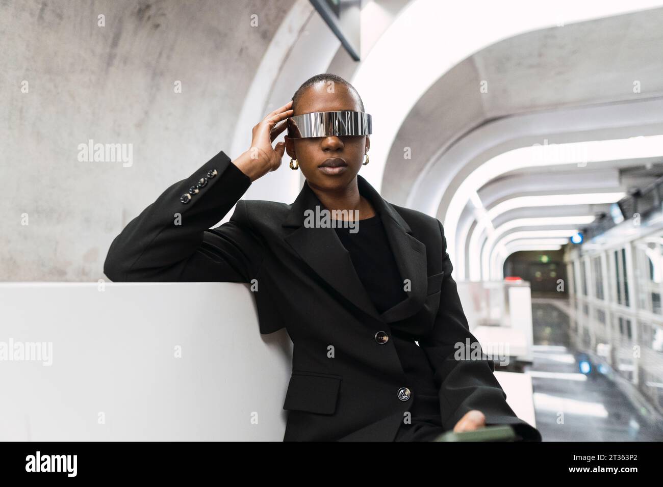 Giovane donna che indossa occhiali intelligenti e si siede alla stazione della metropolitana Foto Stock