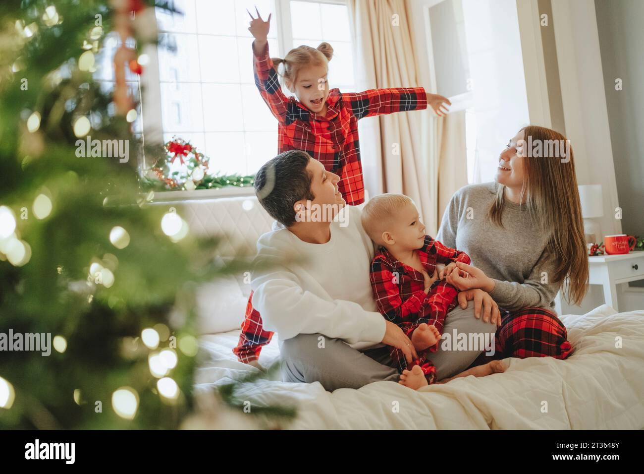 Famiglia che guarda una figlia che balla a letto Foto Stock
