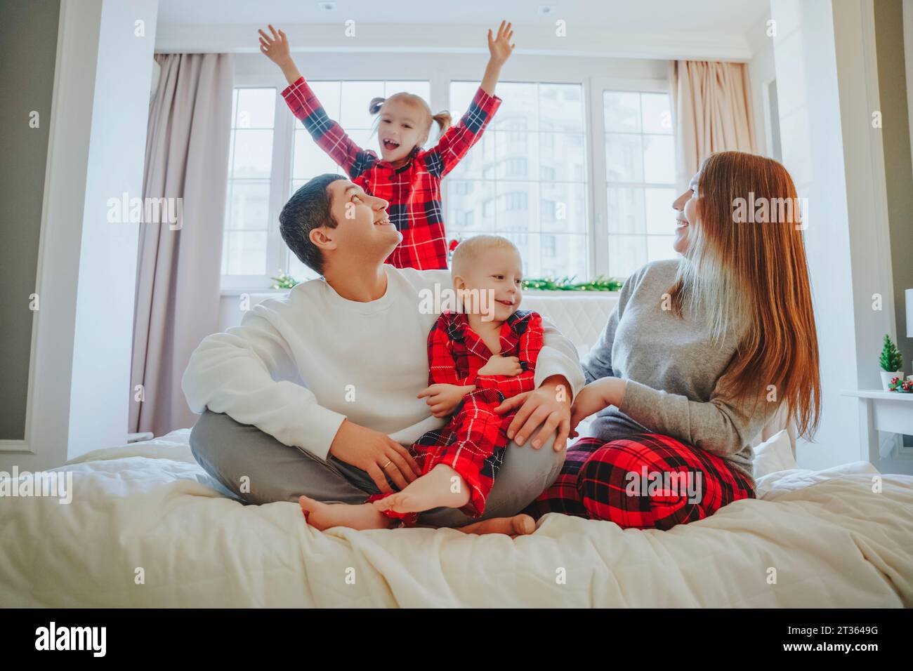 Felice famiglia che trascorre il tempo libero a letto a casa Foto Stock