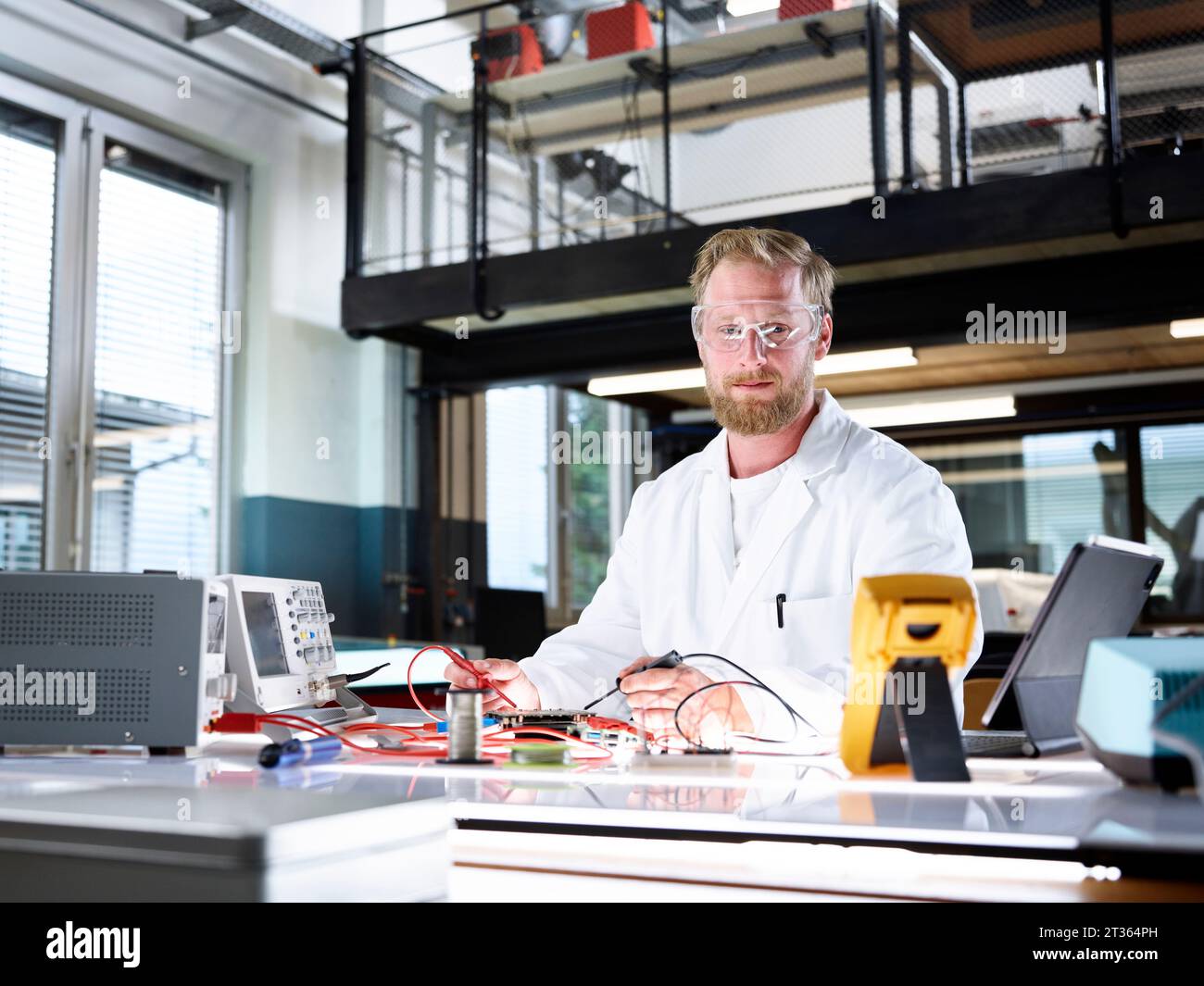 Scienziato sorridente con apparecchiature elettroniche in laboratorio Foto Stock