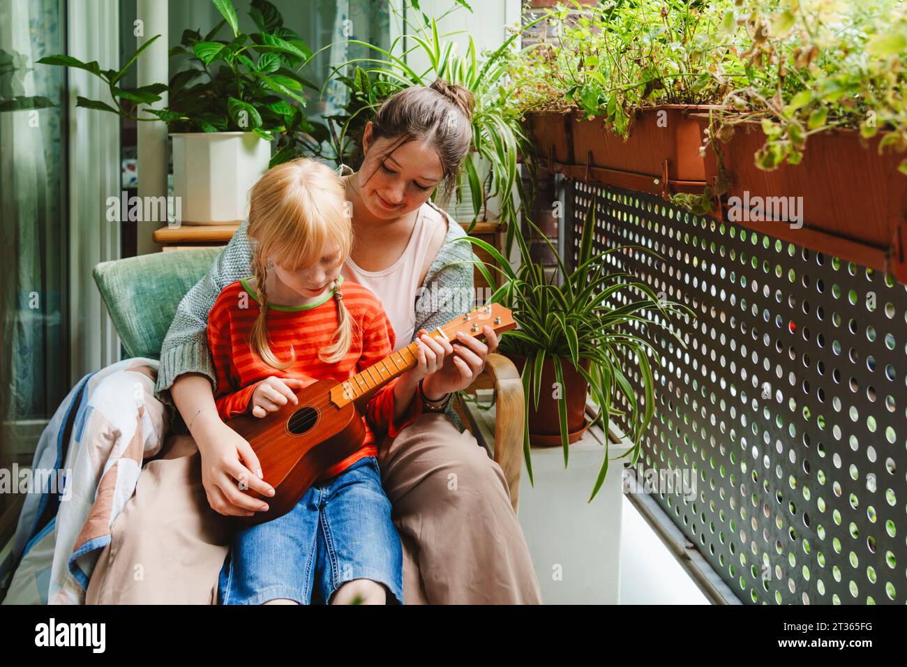 Ragazza adolescente che insegna alla sorella a giocare a ukulele Foto Stock