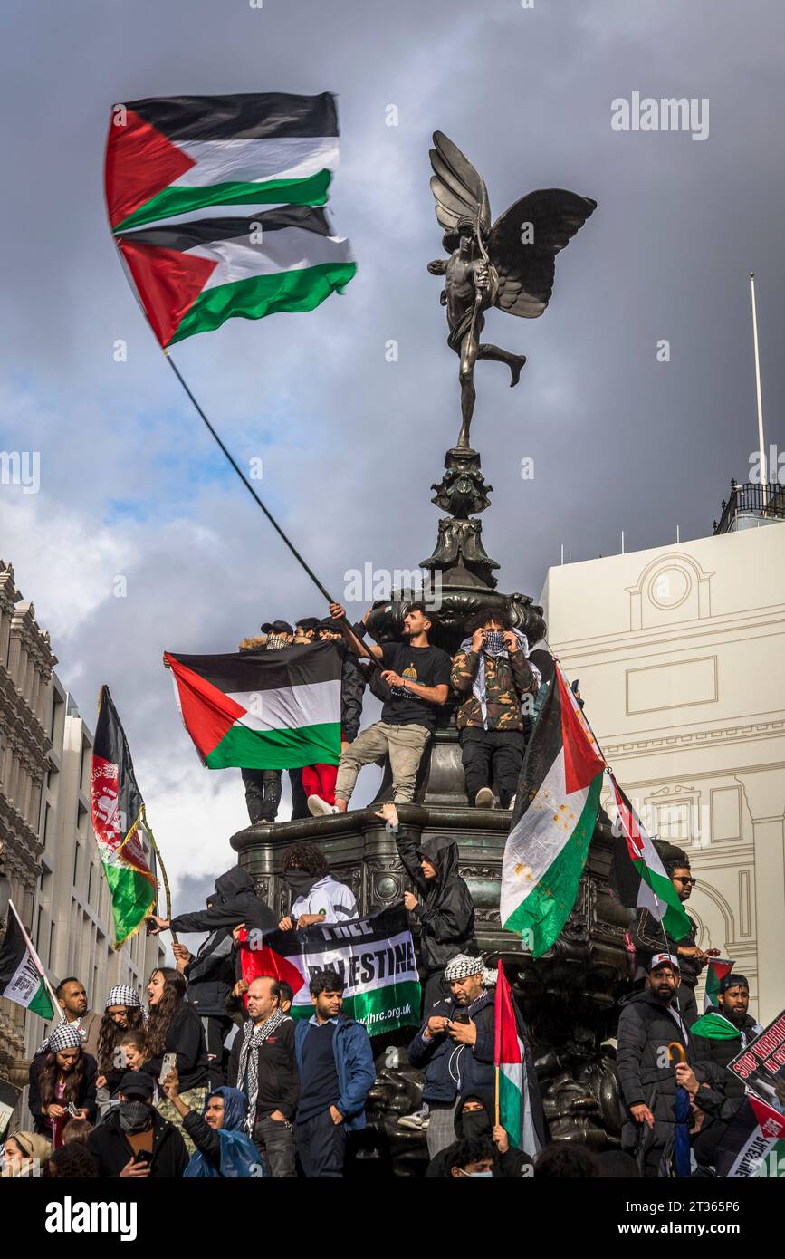 I manifestanti sventolano bandiere in cima alla statua di Eros a Piccadilly Circus, protesta pro-palestinese nel centro di Londra il 21/10/2023, Inghilterra, Regno Unito Foto Stock