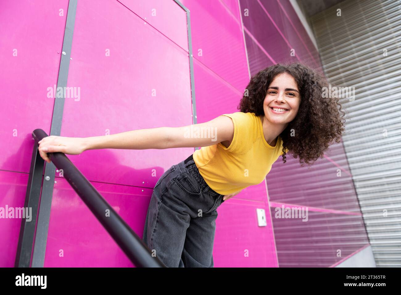 Donna sorridente in piedi davanti alla porta rosa Foto Stock