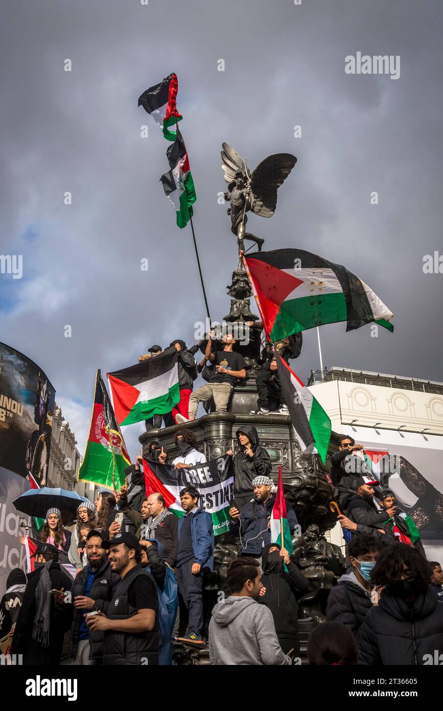 I manifestanti sventolano bandiere in cima alla statua di Eros a Piccadilly Circus, protesta pro-palestinese nel centro di Londra il 21/10/2023, Inghilterra, Regno Unito Foto Stock