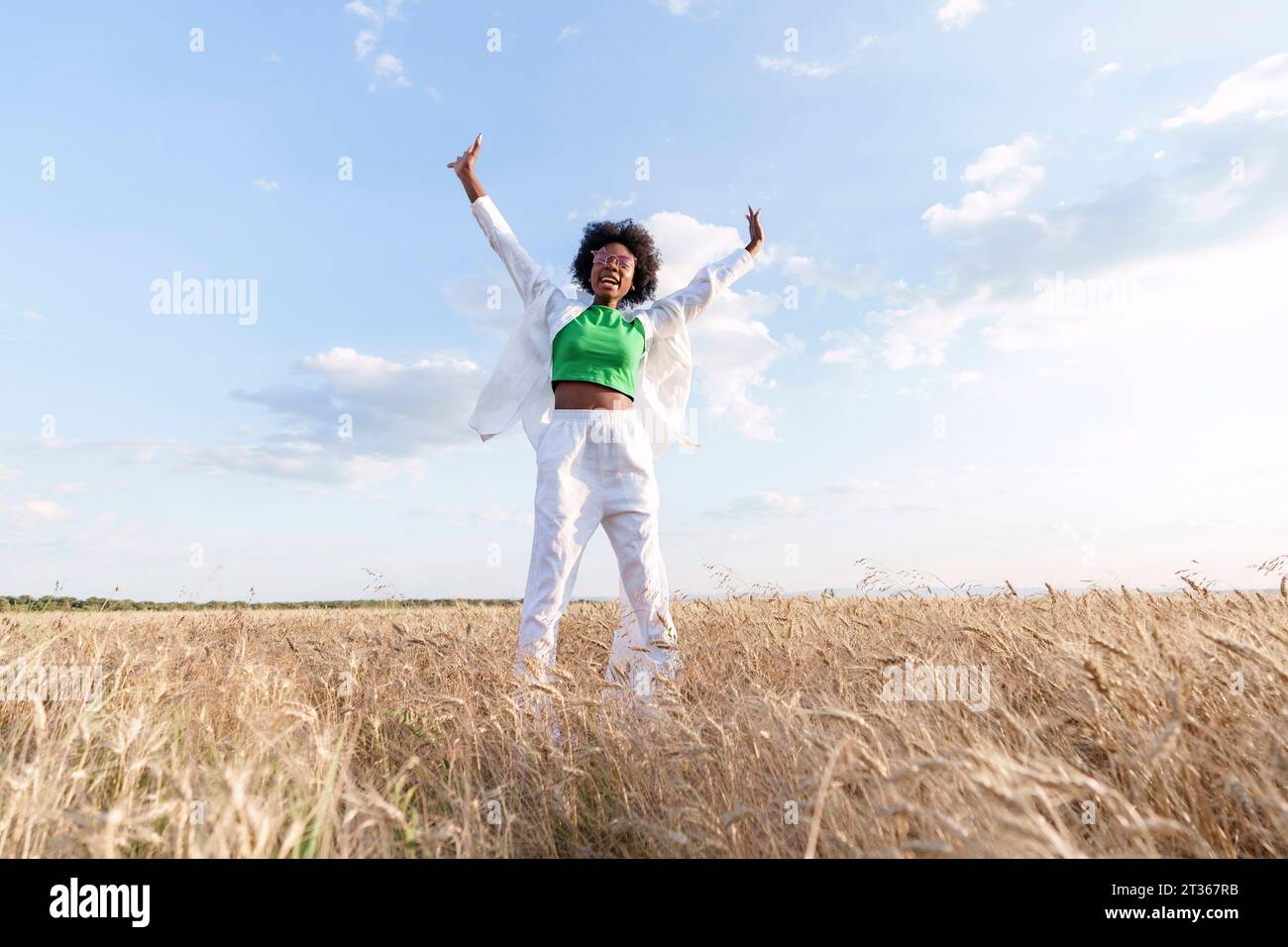 Donna spensierata in piedi con le braccia alzate sul campo Foto Stock