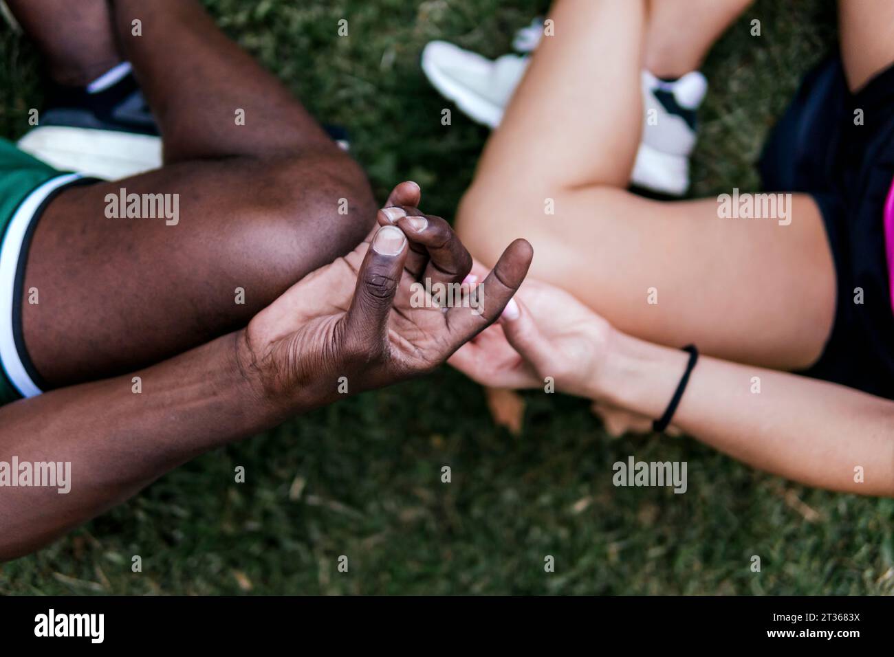 Giovani amici seduti in posizione di loto che meditano al parco Foto Stock
