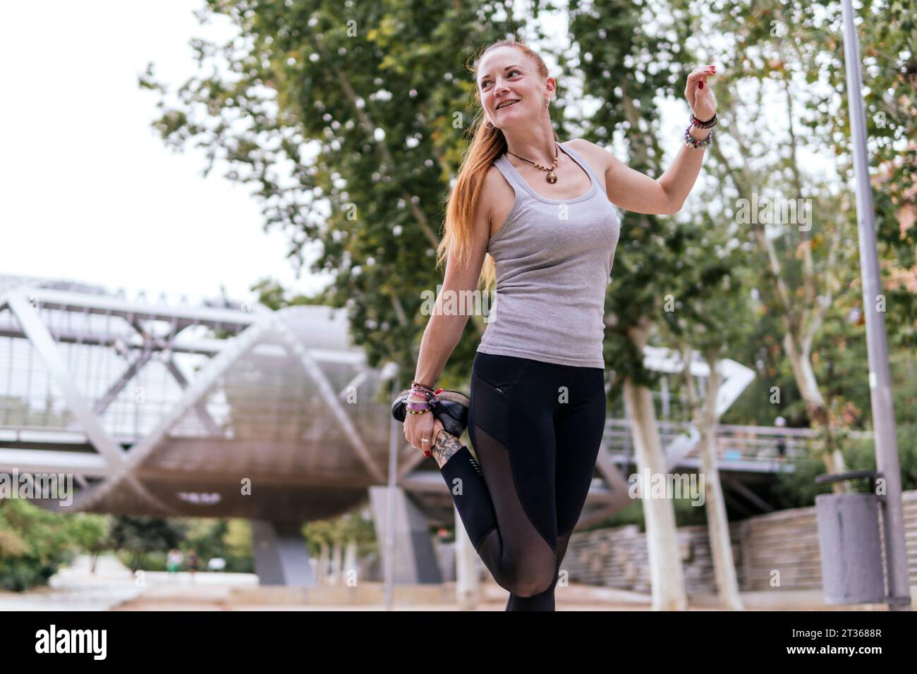 Donna che si sta riscaldando per fare esercizio al parco Foto Stock