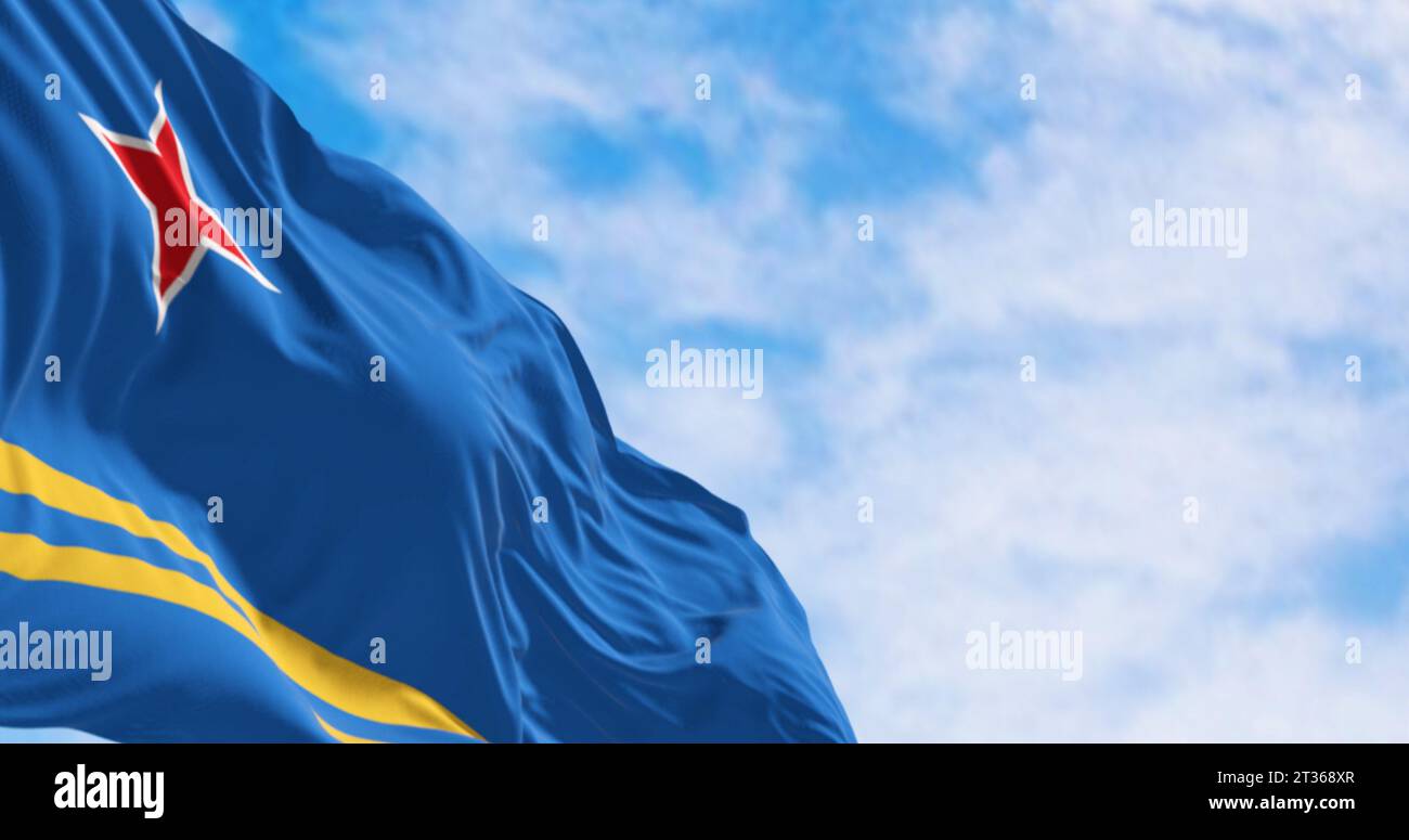 Bandiera di Aruba che sventola nel vento in una giornata limpida. Campo azzurro, 2 strisce gialle, stella rossa a 4 punte. I colori rappresentano il mare, l'abbondanza, la pace ed o Foto Stock