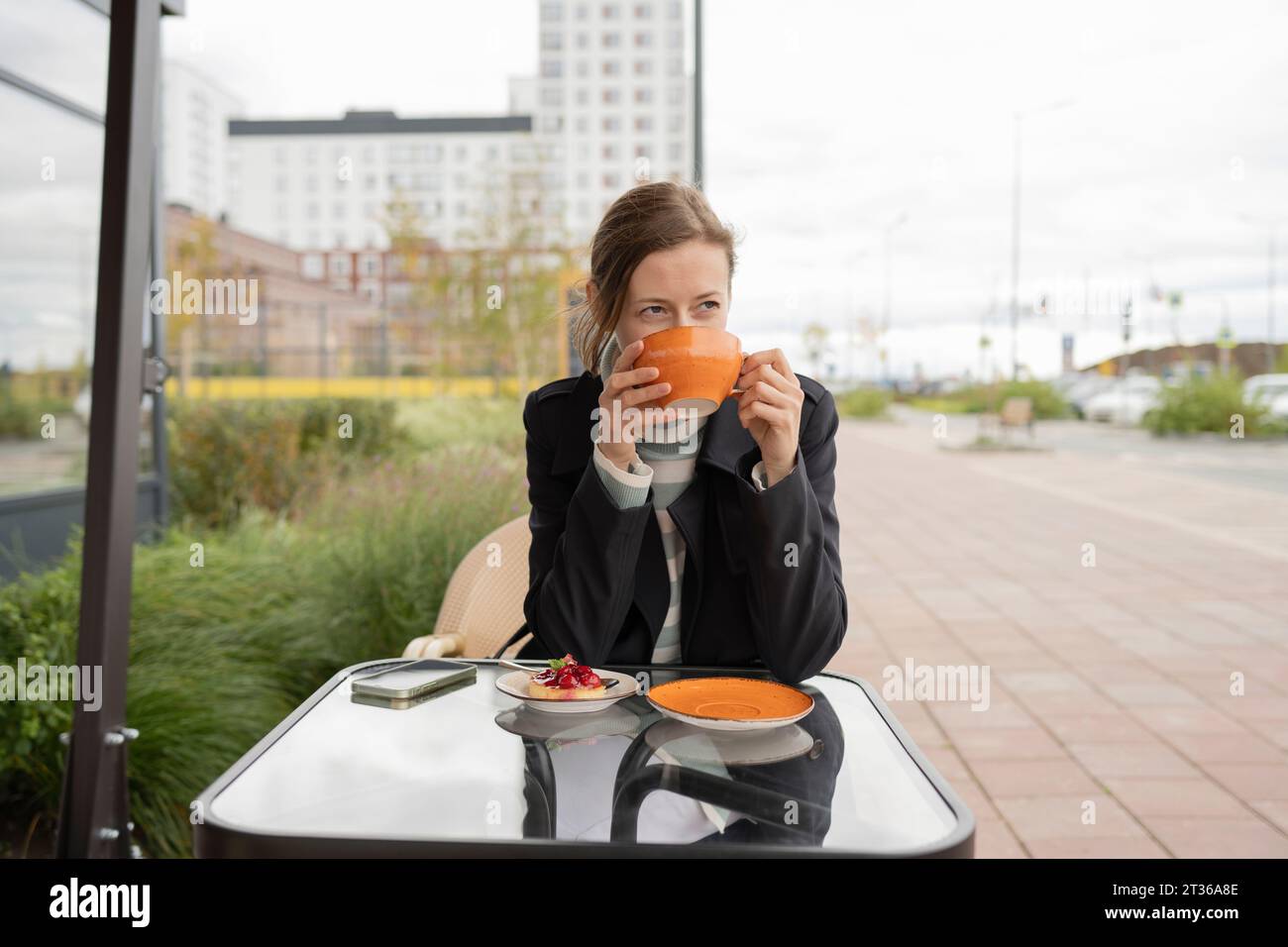 Donna che beve tè al caffè del marciapiede Foto Stock
