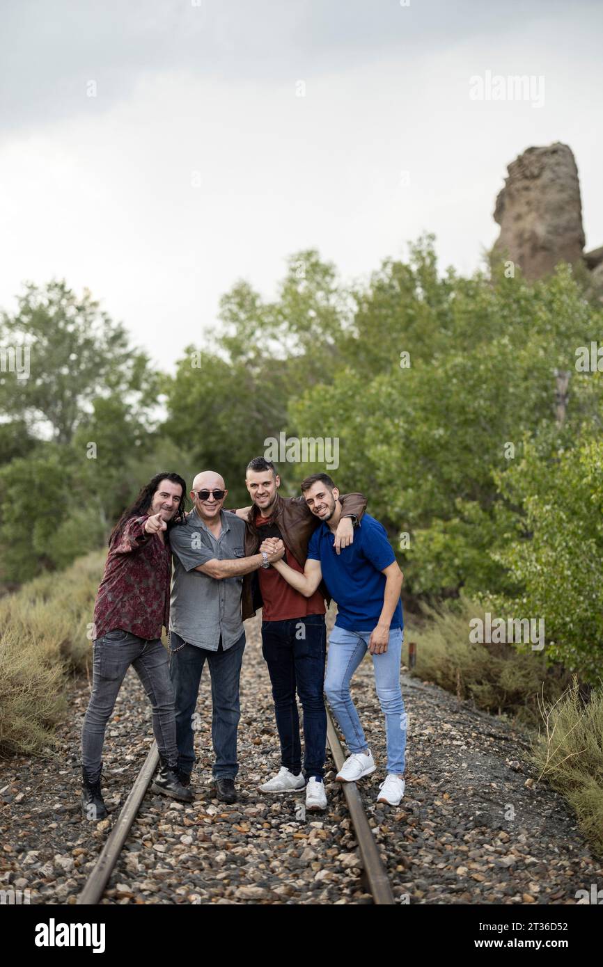 Amici felici in piedi sui binari della ferrovia tra le piante Foto Stock