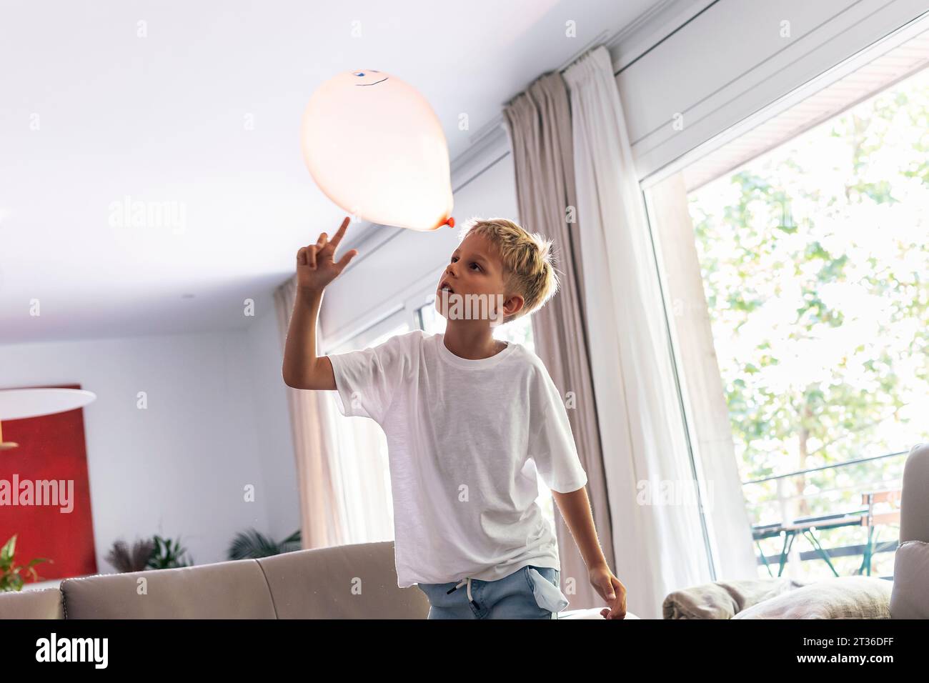 Ragazzo che gioca con il palloncino a casa Foto Stock