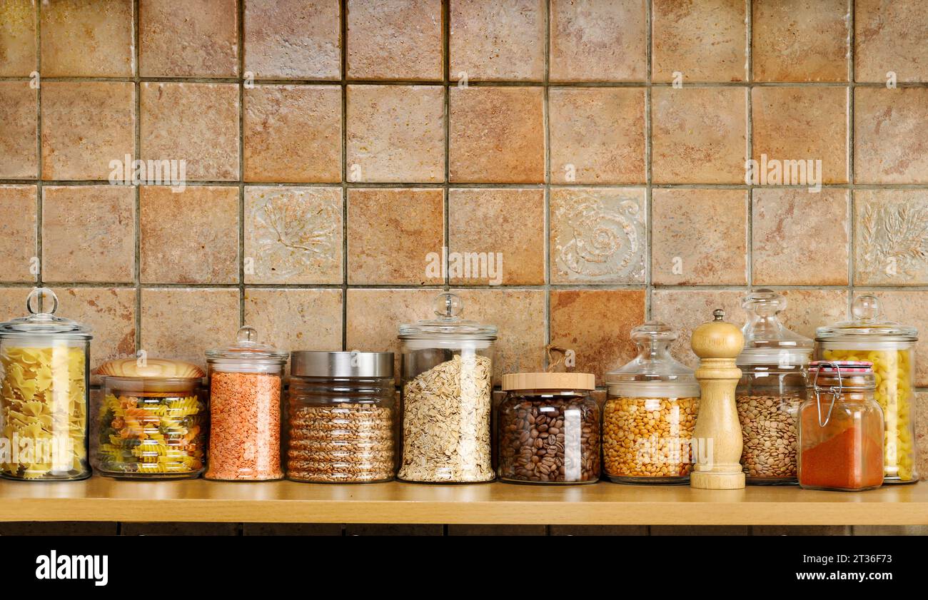 Ripiano da cucina per conservare il cibo in vasetti di vetro su una parete piastrellata Foto Stock
