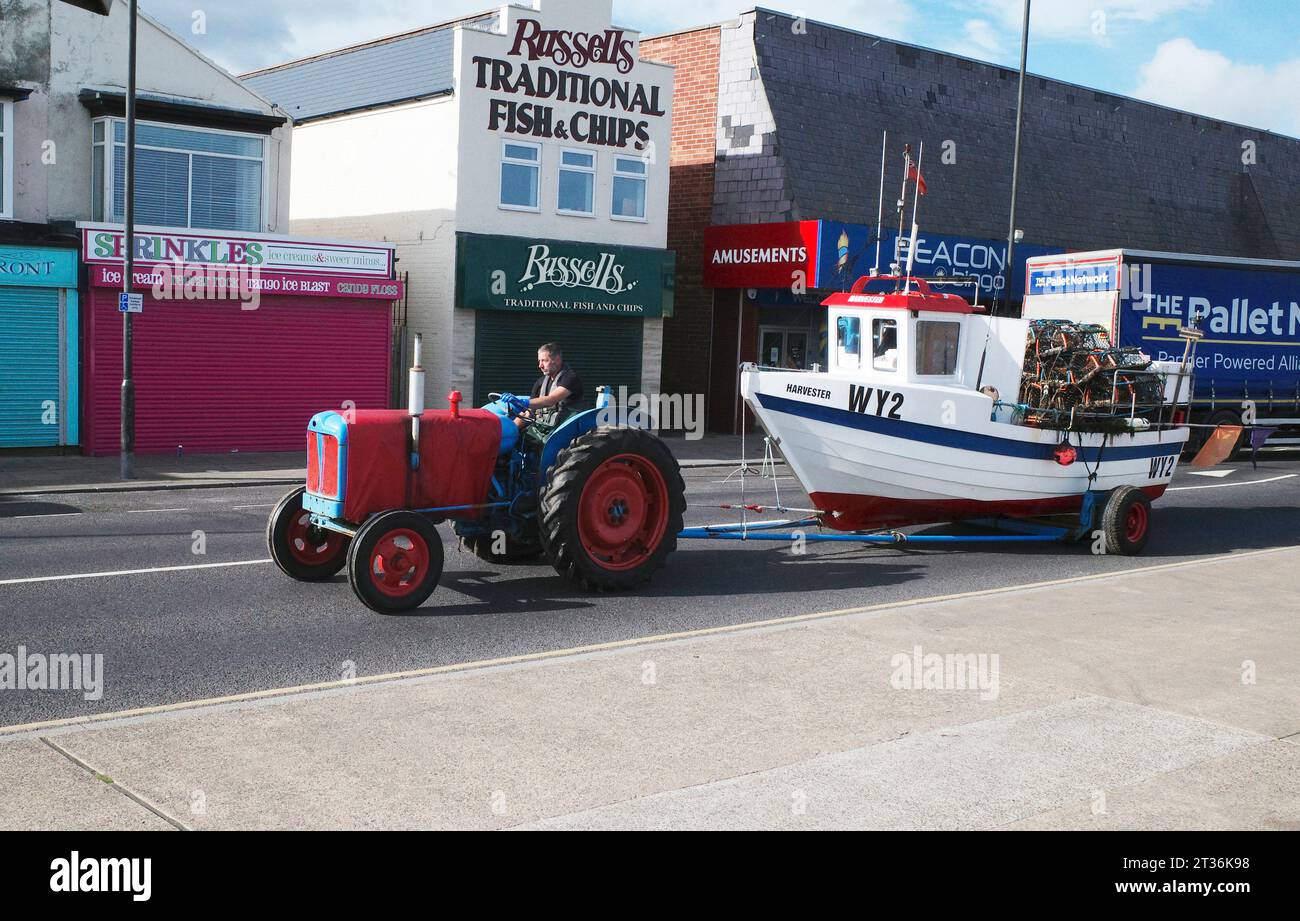 Pescatore alla guida di un trattore che trasporta la sua barca WY2 Harvester dopo una battuta di pesca di granchi o aragoste al largo di Redcar Cleveland Regno Unito, Foto Stock