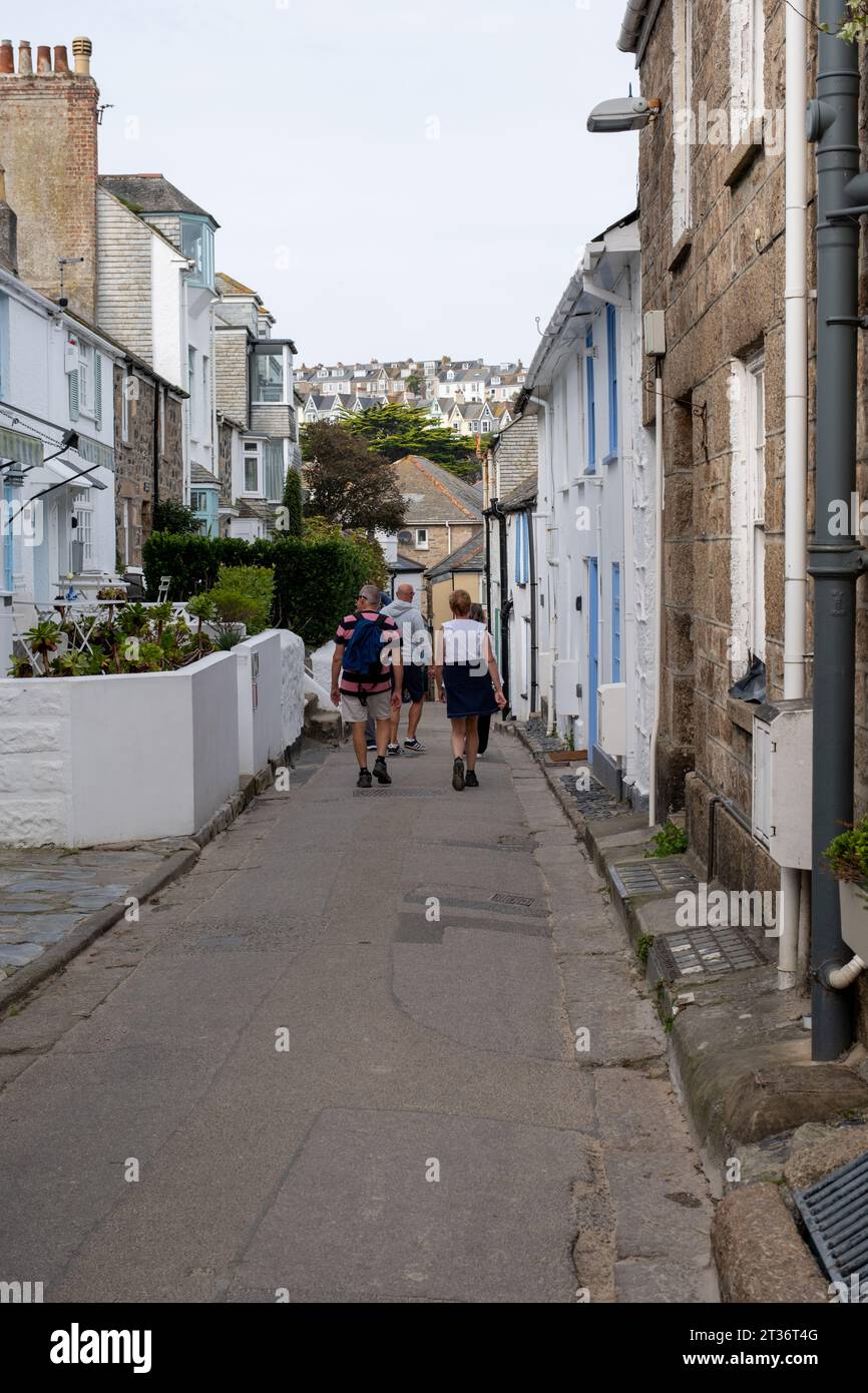 I vacanzieri camminano lungo la stretta strada di St Ives, Cornovaglia, Regno Unito Foto Stock