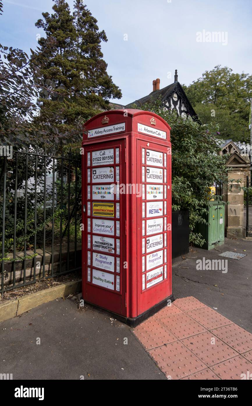 Vecchia cabina telefonica rossa utilizzata per pubblicizzare i corsi di formazione, Monks Road, Lincoln City, Lincolnshire, Inghilterra, REGNO UNITO Foto Stock