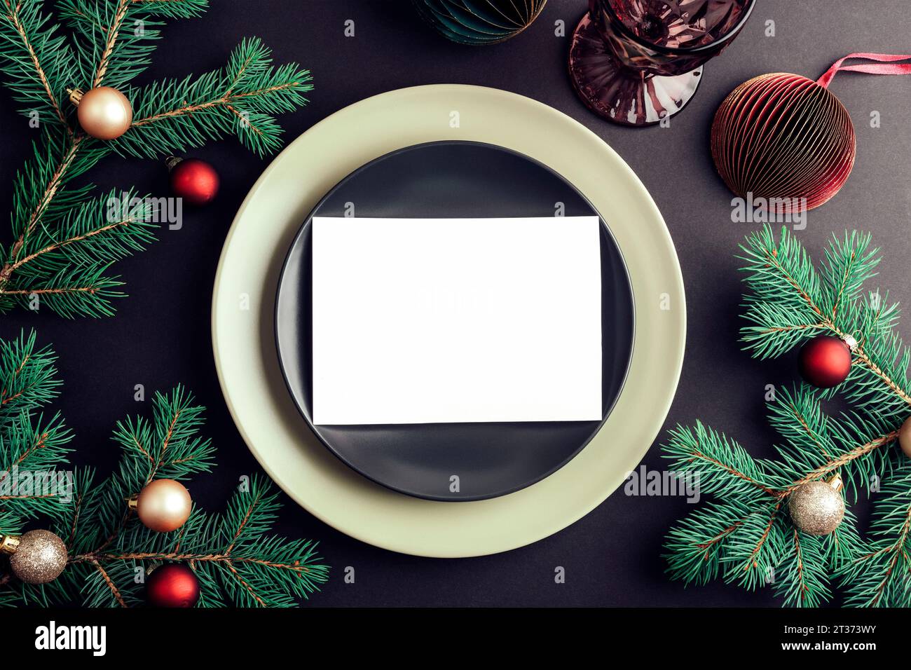 Elegante tavolo con rami di abete e palline di Natale, piastra nera con scheda vuota su sfondo nero. Concetto di Natale. Vista dall'alto, base piatta. Foto Stock