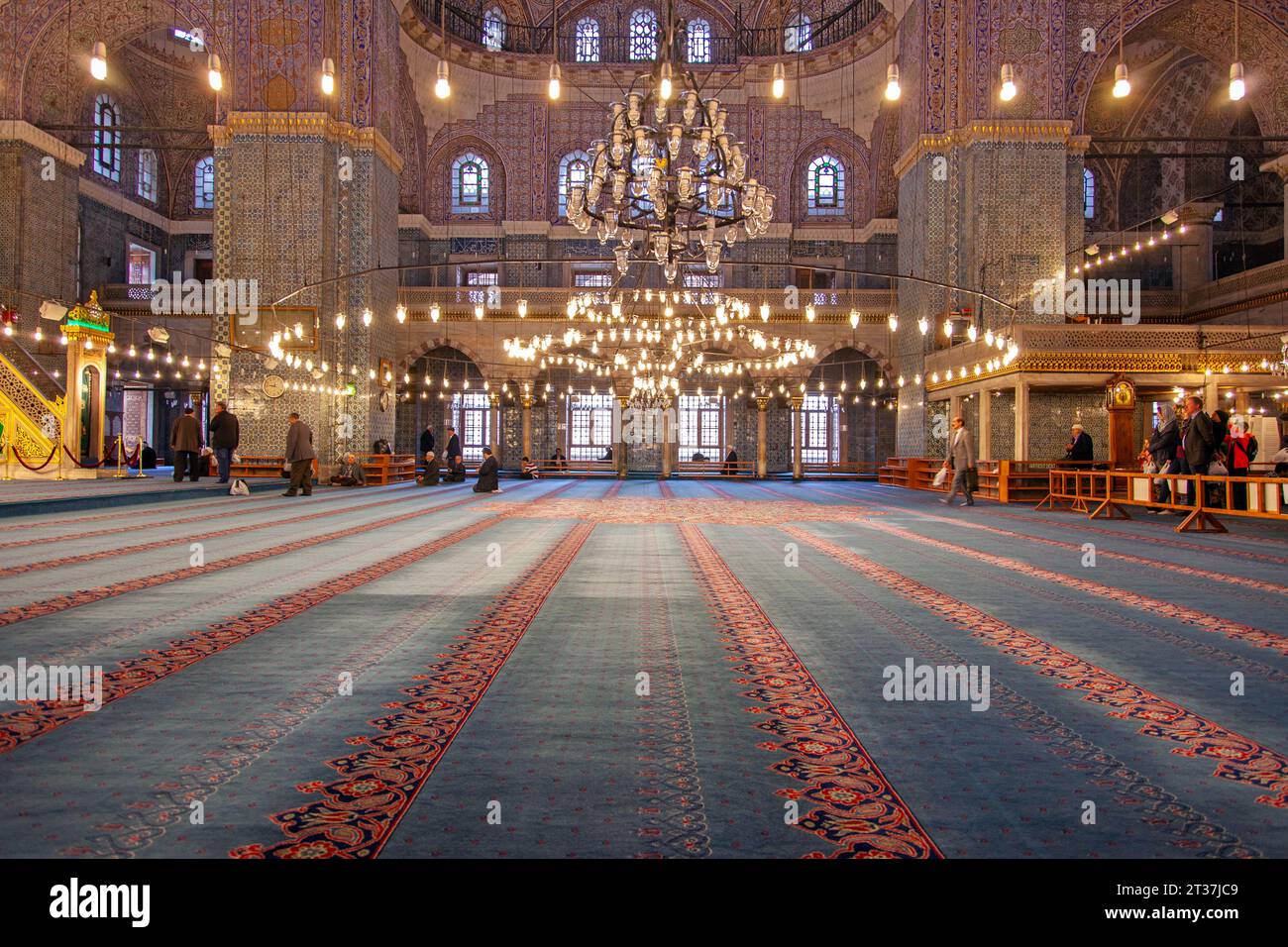 Persone che pregano all'interno della Moschea Blu del XVII secolo illuminata, una storica moschea imperiale dell'epoca ottomana situata a Istanbul, Turchia Foto Stock
