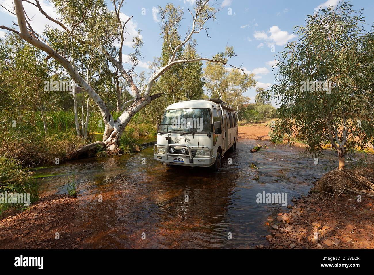 Toyota Coaster camper che attraversa un ruscello poco profondo, Pilbara, Australia Occidentale, Australia Foto Stock